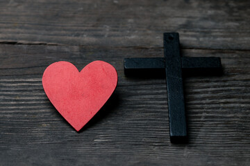 The red heart on black black background including cross beside the heart. The cross is the symbol of Christian religion. God love everyone and help all people. Sunday go to church to pray and worship.