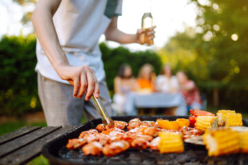 Assorted delicious grilled meat with barbecue grilled vegetables. Сompany of people gathered for barbecue in summer garden. Summer, party, adventure, youth, frienship concept - obrazy, fototapety, plakaty