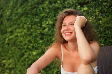Naklejka na ściany i meble Portrait of happy beautiful young woman at sunny summer day smile and look at camera relax on natural background