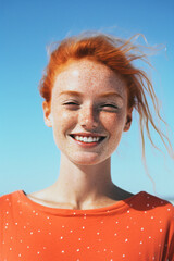 Beautiful close-up portrait of a young woman with red hair and freckles smiling into the camera