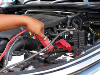 man charging car battery using jumper cables