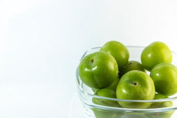 Delicious green plums in a transparent bowl