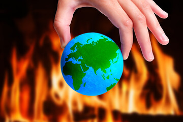 Planet in Peril: Symbolic Earth Model Pinch-Held amidst Blazing Flames