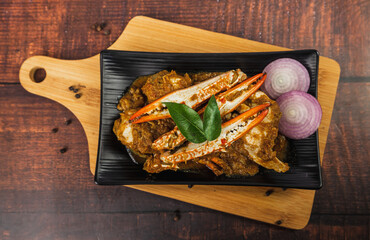 Spicy and delicious crab roast on a wooden table. Stir Fried Crab with Curry Powder garnished with onion, curry leaves and black pepper. Seafood Style. © Sudarsan Thobias