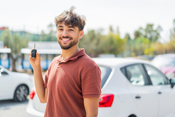 Young Arabian handsome man holding car key at outdoors smiling a lot