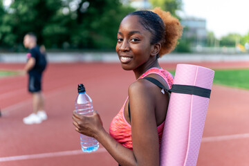 Sporting athletic attire, the determined black woman carries her training equipment—tires, jump...