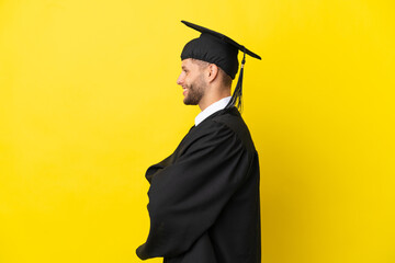 Young university graduate caucasian man isolated on yellow background in lateral position