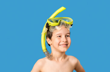 Child with snorkel mask scuba and snorkel standing over blue background looking away to side with...