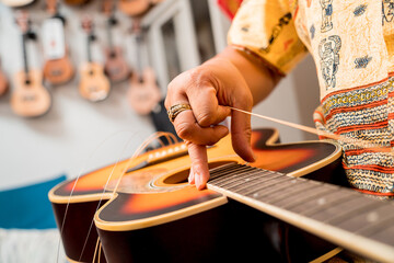 Young musician changing strings on a classical guitar in a guitar shop