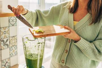 Girl hands prepare a green smoothie, puts fresh spinach leaves in a blender. Healthy eating concept. Vegetarianism, vegan food, fitness food, detox, youth preservation.