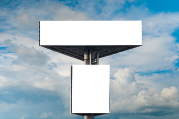 Front view: two blank white billboards or large displays against blue sky with white clouds - mock up. Consumerism, advertising, white screen, template, copy space and mockup concept
