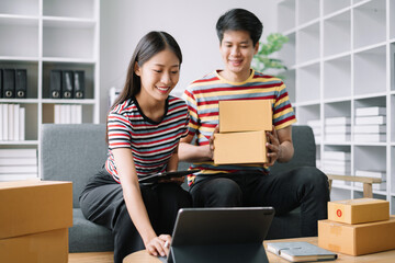 Young couple checklist with cardboard box at home - Business online and delivery concept.