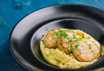 mashed potatoes with meat cutlets on black plate