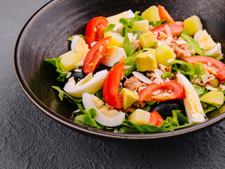 Tuna fish salad with eggs, lettuce, cherry tomatoes, avocado and olives