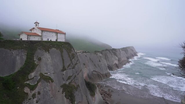 Hermitage of San Telmo with the Dragonstone cave located below it on a foggy day in Zumaia, Basque Country
