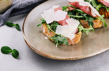 Bruschetta with beef, arugula and parmesan cheese