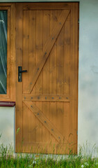 Brązowe drewniane drzwi z czarna klamka i ozdobnymi listwami  - obrazy, fototapety, plakaty