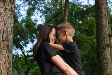 Mom and son are walking in the park and hugging