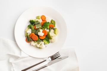 steamed vegetables on a white plate on a white background.