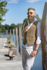 Set portrait. Man smoking a cigar by the river with long beard, shirt and curled moustache.
Dark...