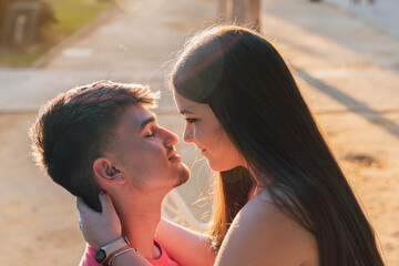 Joven, guapa y  atractiva pareja, segundos antes de iniciar su primer beso, sentados en un banco de un parque.