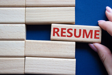 Resume symbol. Concept word Resume on wooden blocks. Businessman hand. Beautiful deep blue background. Business and Resume concept. Copy space.