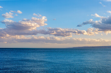 scenic blue seascape of sunset or sunrise above water with beautiful colorful evening clouds