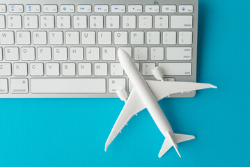 Airplane model and computer keyboard on blue background. Booking flight airways tickets online concept. Search easy best flight, plan, compare lowest and cheap air fare tickets, deal.