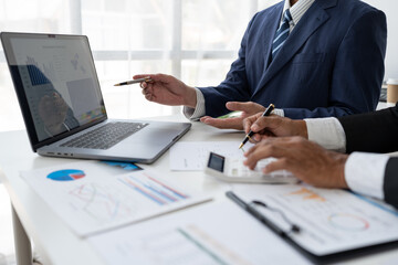 Financial analyst analyzing business financial report on laptop and graph document during discussion in company showing successful teamwork business meeting concept marketing.