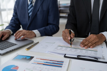 Financial analyst analyzing business financial report on laptop and graph document during discussion in company showing successful teamwork business meeting concept marketing.