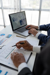 Financial analyst analyzing business financial report on laptop and graph document during discussion in company showing successful teamwork business meeting concept marketing.