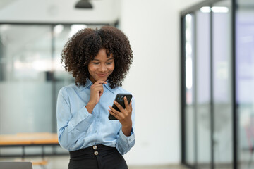 Young african american businesswoman sitting on the desk at the office while making a video call with a business colleague in receiving good news on modern business contracts.