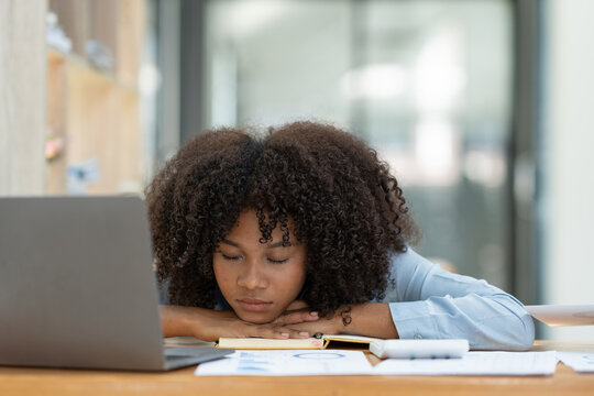Tired african american businesswoman lying on the table in startup office after working at management statistics Workaholic black manager planning company strategy.