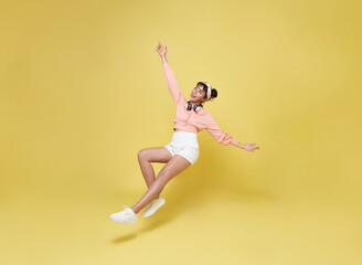 Fototapeta na wymiar Happy smiling asian girl relaxing floating in mid-air isolated on yellow background.