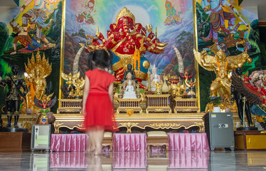 Motion blur girl walks in front of an altar in a Buddhist temple, Thailand