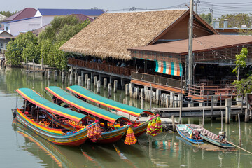 Traditional wooden boats decorated with flowers on the nose are moored at the jetty, Thailand