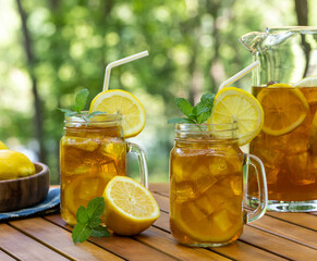 Ice tea in glass and pitcher with lemon and mint