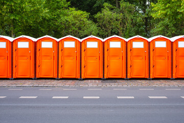 A line of orange plastic portable chemical toilets