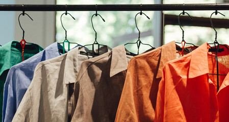 Choice of fashion shirt of different colors on metal hangers in a retail shop. Reduce Reuse Recycle concept. Horizontal photo - Powered by Adobe