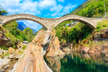 Ancient double arch stone Roman bridge (Ponte dei Salti) over the clear water of the Verzasca river in Lavertezzo ,Verzasca Valley, Ticino Canton, Switzerland