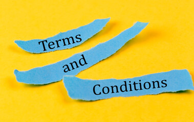 TERMS AND CONDITIONS text on a blue pieces of paper on yellow background, business concept