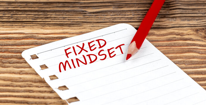Word FIXED MINDSET on a paper with ped pencil on wooden background