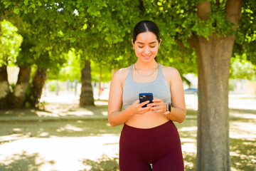 Happy latin woman texting on her phone and ready to exercise