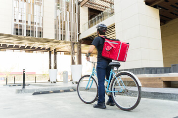 Rear view of a delivery worker with a backpack riding a bike