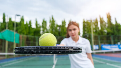 Closeup of female tennis player hand holding racket and ball while playing tennis on a sunny day.