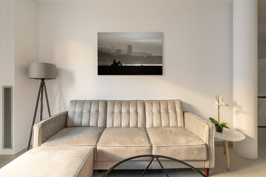 Comfortable beige corner sofa near a glass coffee table on a picture in a cozy living room. Concept of a lounge zone for meeting guests or relaxing after work