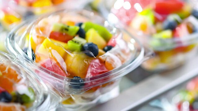 Plastic boxes with pre-packaged fruit salads, put up for sale in a commercial refrigerator
