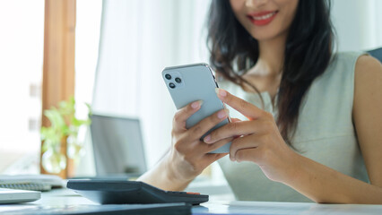 Smiling female employee checking social media, chatting on smart phone.