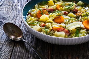 Hot cabbage soup with bacon on wooden table
