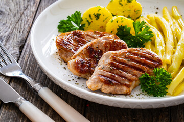 Grilled meat and yellow asparagus on wooden table
